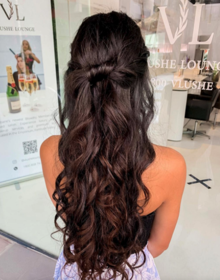 A woman with long black hair has a bouncy blowdry at Vlushe Lounge